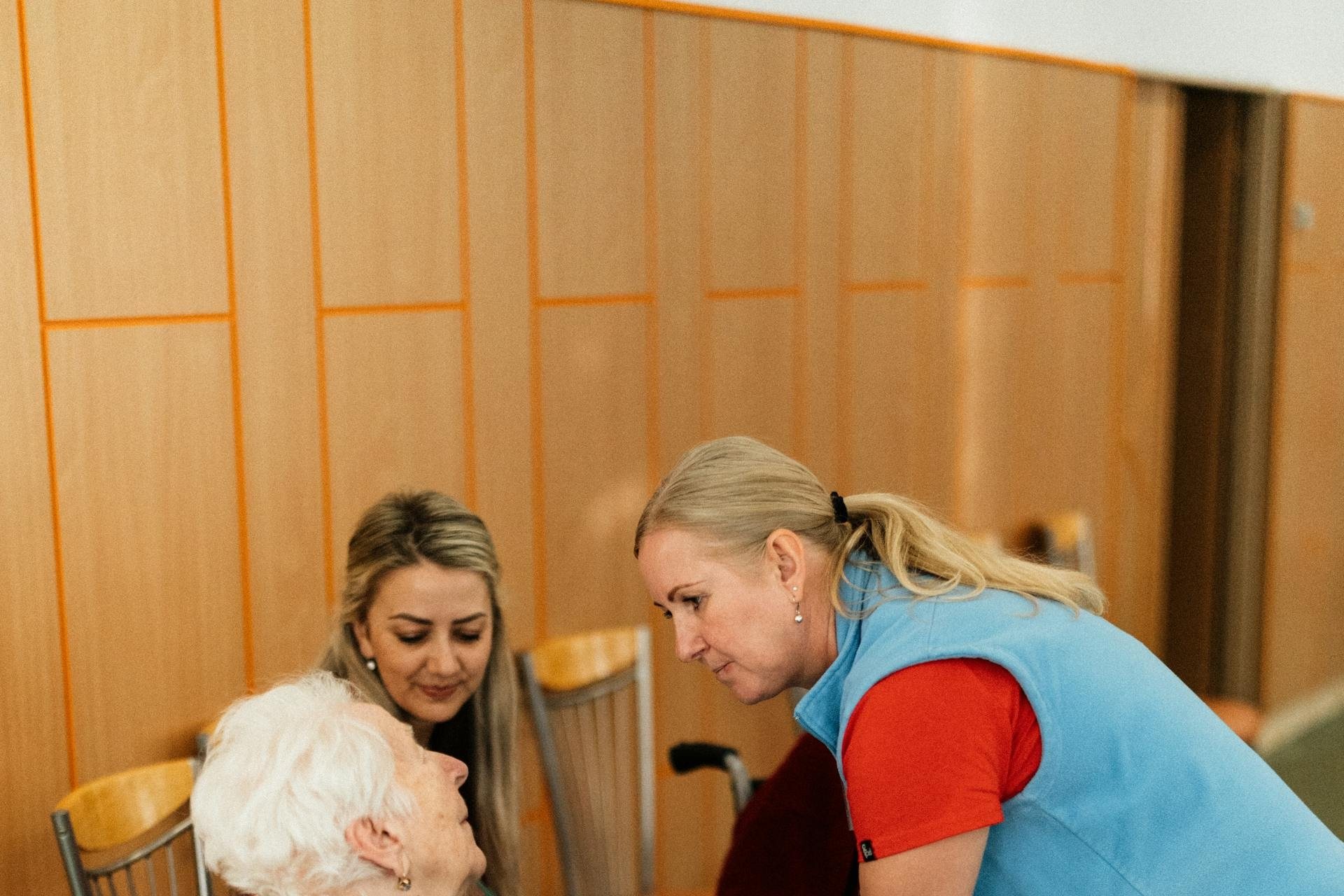 Caregiver leaning in to speak with an older woman