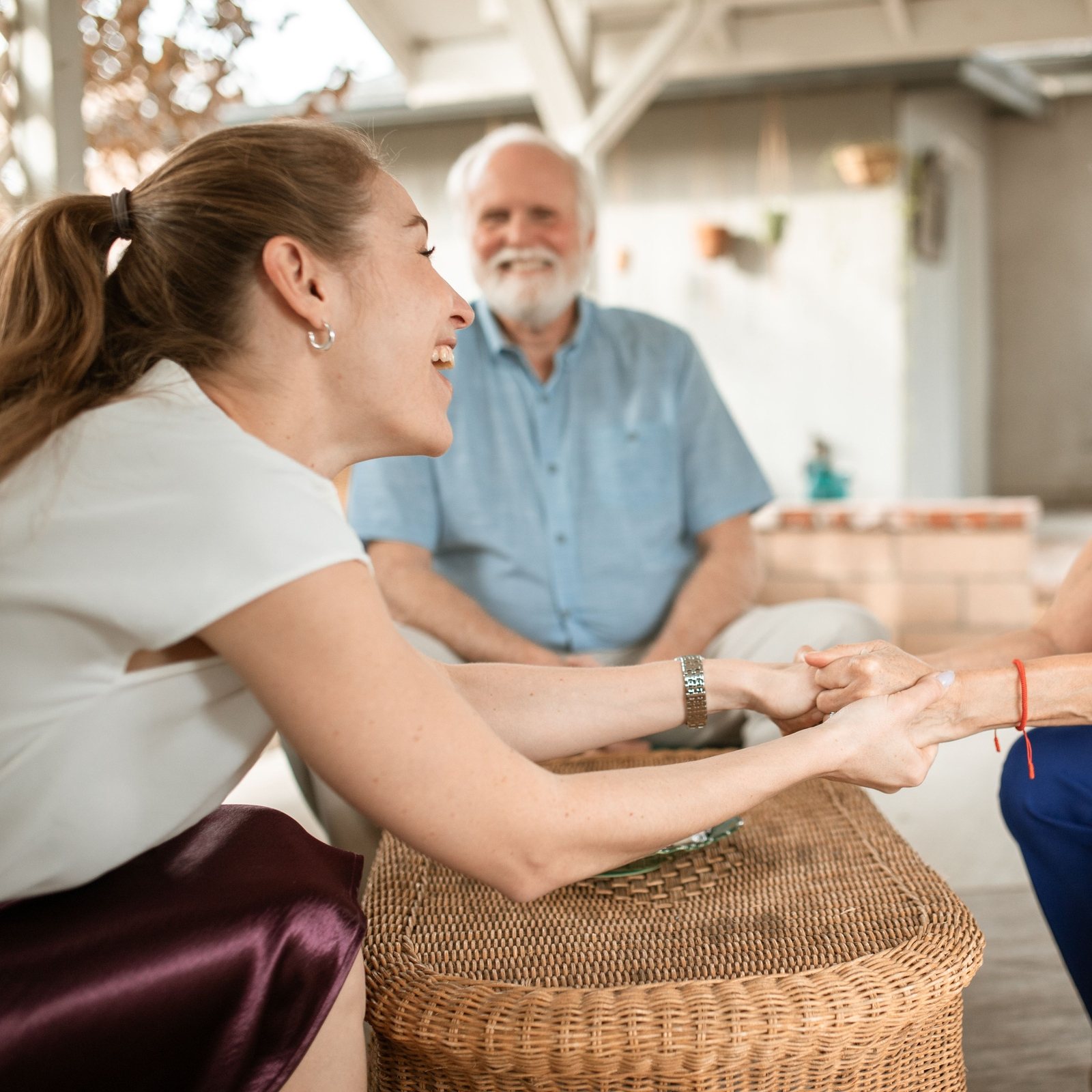 Caregiver holding hands with two older residents on the patio