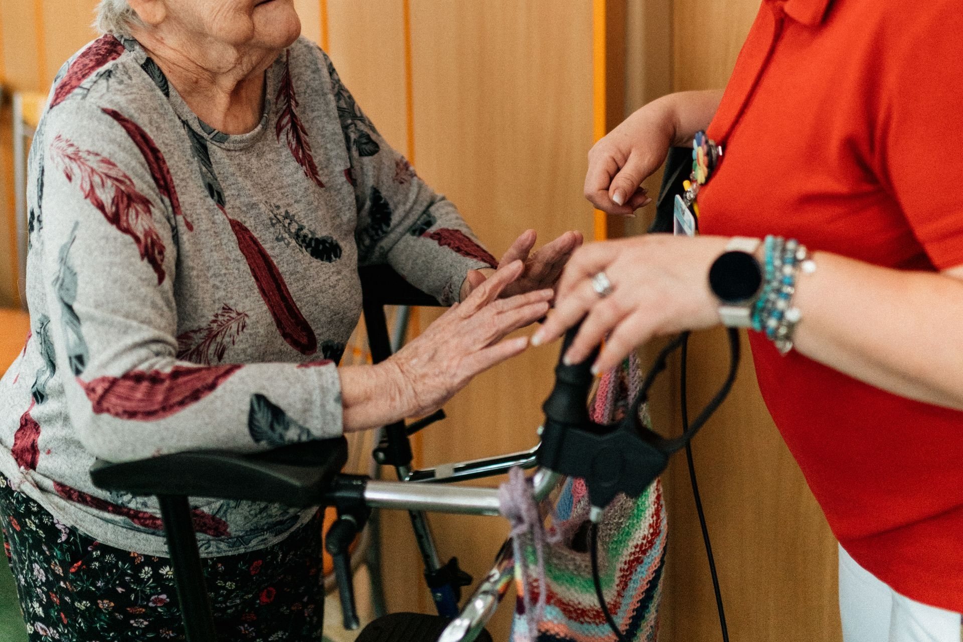 Caregiver steadying an older woman at her rollator indoors